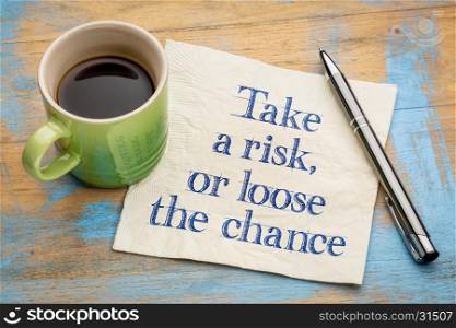 Take a risk or loose the chance - handwriting on a napkin with a cup of espresso coffee