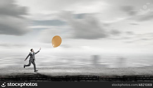 Take a short break. Emotional businessman running and trying to catch color balloon