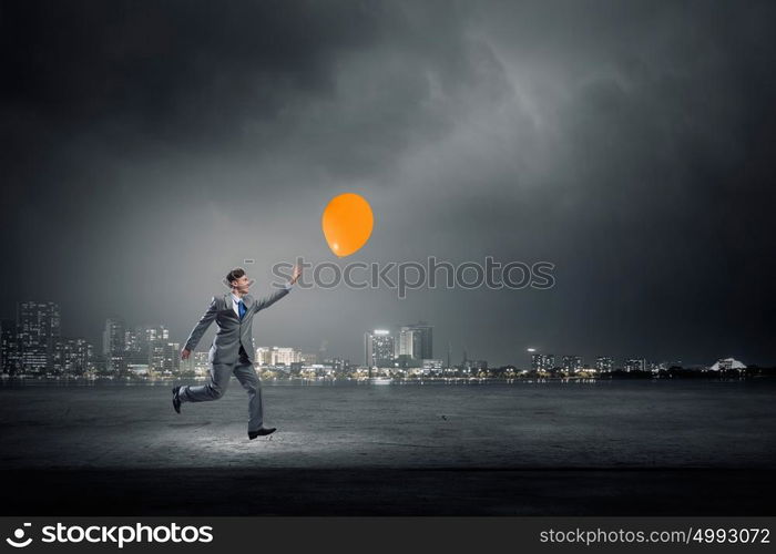 Take a short break. Emotional businessman running and trying to catch color balloon