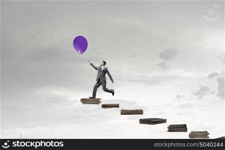 Take a short break. Emotional businessman running and trying to catch color balloon