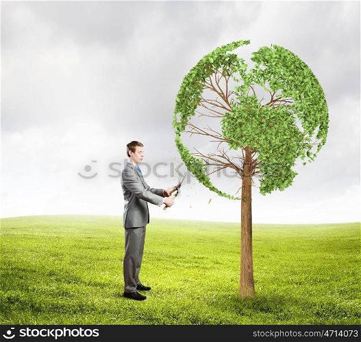 Take care of our home. Young businessman cutting tree with scissors in shape of Earth planet