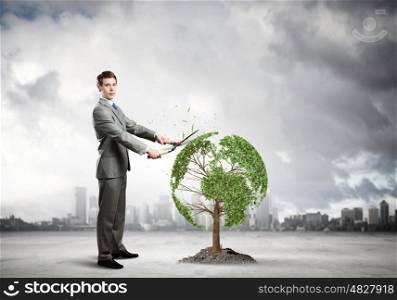 Take care of our home. Young businessman cutting tree with scissors in shape of Earth planet