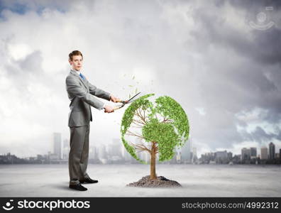 Take care of our home. Young businessman cutting tree with scissors in shape of Earth planet