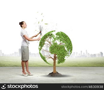Take care of our home. Young businesswoman cutting tree with scissors in shape of Earth planet