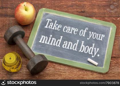 Take care of your mind and body - slate blackboard sign against weathered red painted barn wood with a dumbbell, apple and tape measure