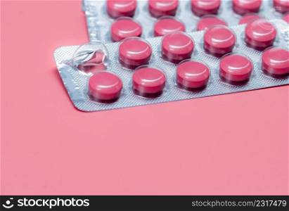 Take pill concept. Pink tablets pills in blister pack on pink background. Prescription drug. Pharmaceutical industry. Pill reminder or medication reminder background. Vitamin, mineral, and supplement.