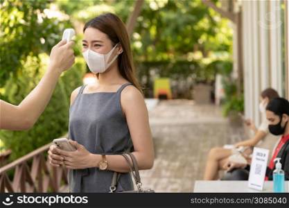 Take Temperature for customer with face mask before getting in restaurant with social distance queue in line new normal after coronavirus covid-19 pandemic. Restaurant New normal concept.