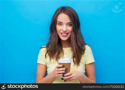 takeaway and people concept - smiling young woman or teenage girl in yellow t-shirt with coffee cup over bright blue background. young woman or teenage girl with coffee cup