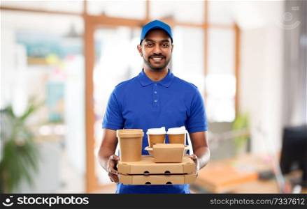 takeaway service and people concept - happy indian delivery man with food and drinks in blue uniform over office background. indian delivery man with food and drinks at office