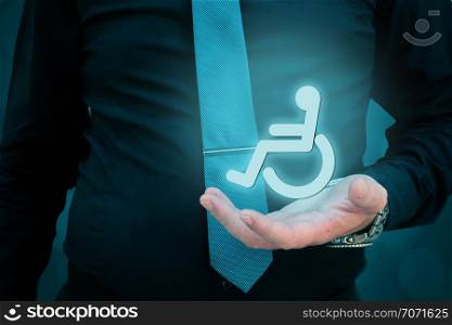 Taking care of persons with disability concept.Businessman holding hologramic weelchair in his hand.. Taking care of persons with disability concept.Businessman holding hologramic weelchair in his hand