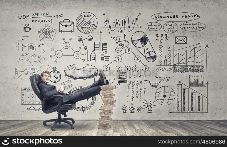 Taking coffee break. Young handsome businessman sitting in chair with his legs on pile of books