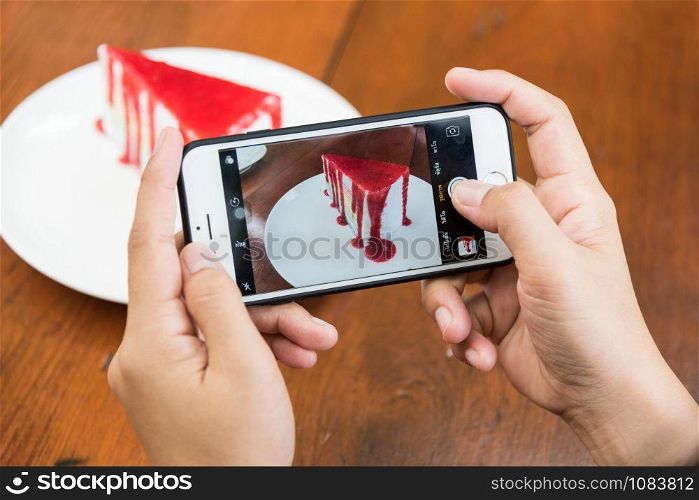 Taking photo of Sliced tasty strawberry cake on wooden table background