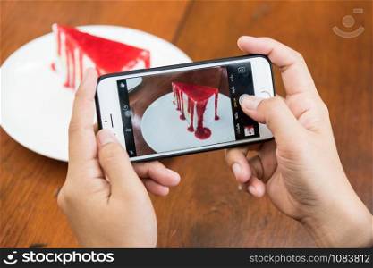 Taking photo of Sliced tasty strawberry cake on wooden table background