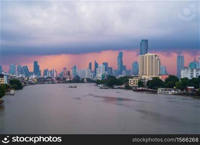 Taksin Bridge with Chao Phraya River, Bangkok Downtown. Thailand. Financial district and business centers in smart urban city. Skyscraper and high-rise buildings with storm rain.