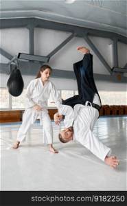 Talented female student throwing aikido teacher on floor during sparring and self defense training in gym. Talented female student throwing aikido teacher on floor