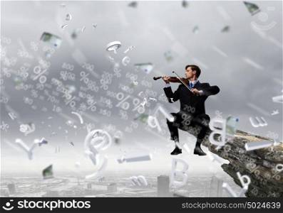 Talented people are to be on top!. Businessman sitting on rock edge and playing violin