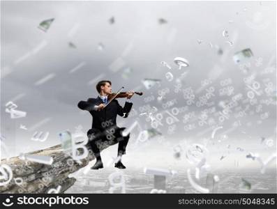 Talented people are to be on top!. Businessman sitting on rock edge and playing violin