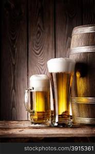 Tall glass and mug beer on the background of wooden barrels. Tall glass and mug beer
