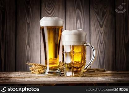 Tall glass and mug of light beer with ears barley on wooden background. Tall glass and mug of light beer with ears barley