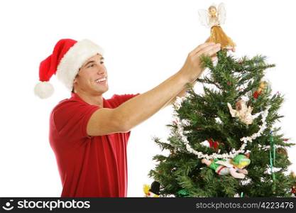 Tall handsome young man placing the angel on the top of the tree. Horizontal view isolated on white.