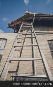Tall ladder at an old building with damaged roof
