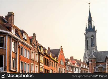 Tall medieval bell tower rising over the street with old european houses, Tournai, Walloon municipality, Belgium