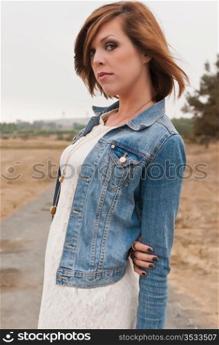Tall pretty brunette in a white dress and denim jacket