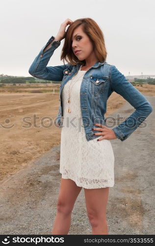 Tall pretty brunette in a white dress and denim jacket