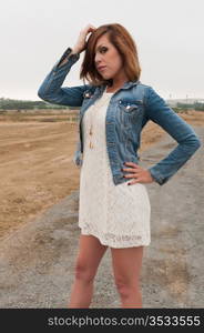 Tall pretty brunette in a white dress and denim jacket