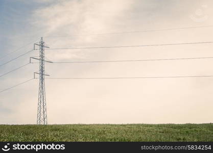 Tall pylons with wires on a green field