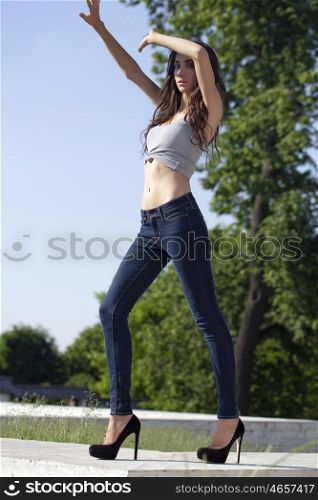 Tall, slim model in blue jeans on the background of blue sky