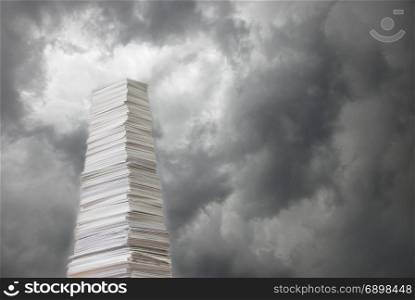 Tall stack of paper against a background of stormy sky covered with dark clouds