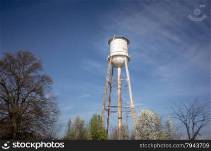 Tall water tower with cloudy blue sky background