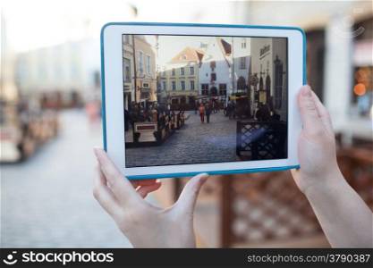 TALLINN, ESTONIA - APRIL 22, 2014: Close-up shot of womans hands using touchpad to make video or photo of ancient street in Tallin old city