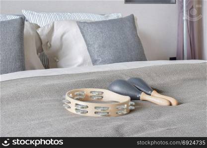 Tambourine and maracas setting on bed with gray color scheme bedding in the bedroom