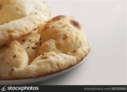 Tandoori rotis topped with sesame seeds against white background
