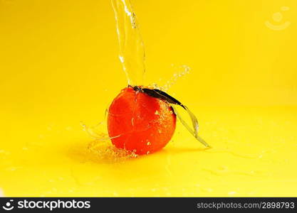 tangerine and water splashes on yellow, close up