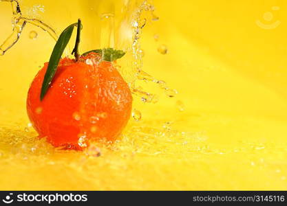 tangerine and water splashes on yellow, close up