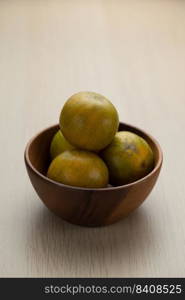 Tangerine in a wooden bowl on the wooden table