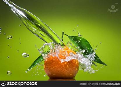 Tangerine with green leaves and water splash on green background