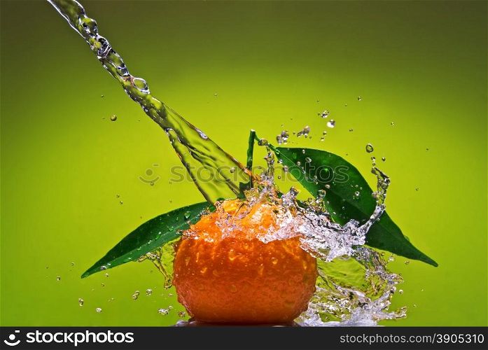 Tangerine with green leaves and water splash on green background