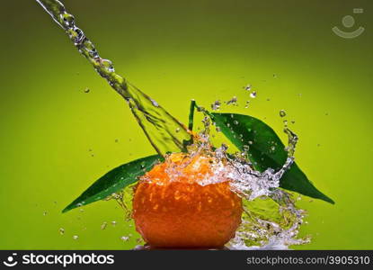 Tangerine with green leaves and water splash on green background