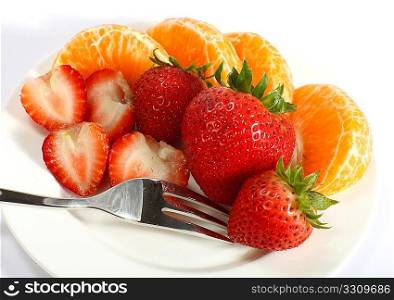Tangerines and strawberries on a white plate with a fork