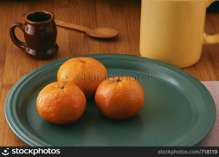 Tangerines. close-up still life of tangerines on a plate and with table elements such as cup and cutlery. wooden bottom. Mandarin background