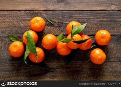 Tangerines, fresh mandarin oranges, clementines with leaves on wooden background. Top view, copy space