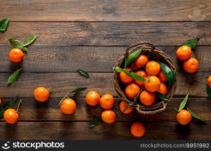 Tangerines, fresh mandarin oranges, clementines with leaves on wooden background. Top view, copy space