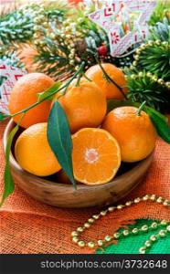 Tangerines in bowl with Christmas decorations, selective focus