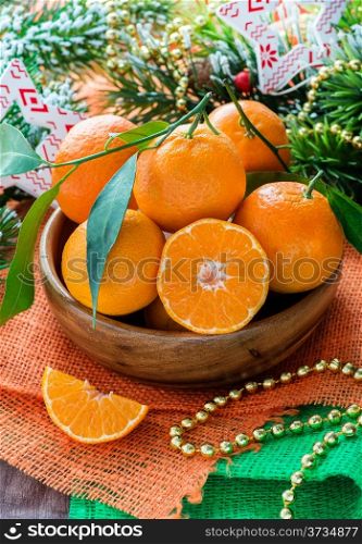 Tangerines in bowl with Christmas decorations, selective focus