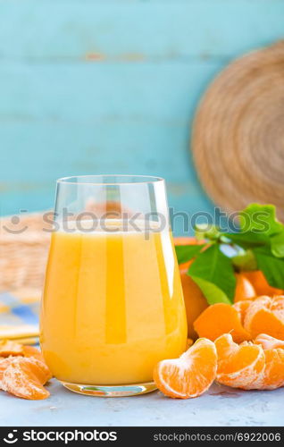 Tangerines, peeled tangerines and tangerine juice in glass. Mandarine juice and fresh fruits with leaves.