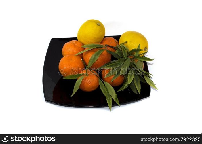 tangerines with a lemon spread out on a black plate